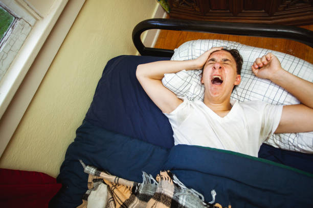 istock Young Man Waking Up Early or Sleeping Late in Bed 1284946582