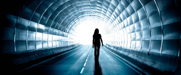 silhouette di una donna in un tunnel buio con uscita leggera - luce alla fine del tunnel foto e immagini stock