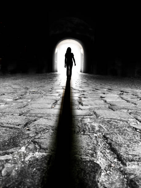 istock Silhouette of a woman in a dark tunnel with a light exit 1284950301