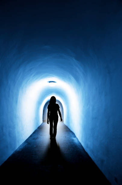 istock Silhouette of a woman in a dark tunnel with a light exit 1284950312