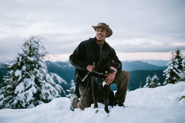 Hiker and Dog in Snow Covered Pacific Northwest An African American man and his dog hiking in the snow covered mountain areas of Washington state, USA.  An exciting winter adventure. snow hiking stock pictures, royalty-free photos & images