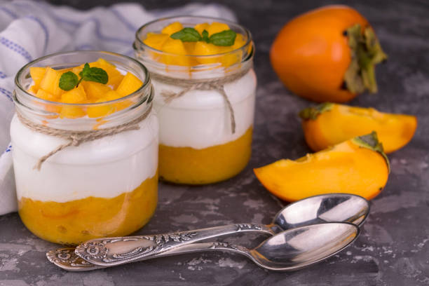 istock Yogurt with persimmon in jars on a gray background. Close-up. 1284955601