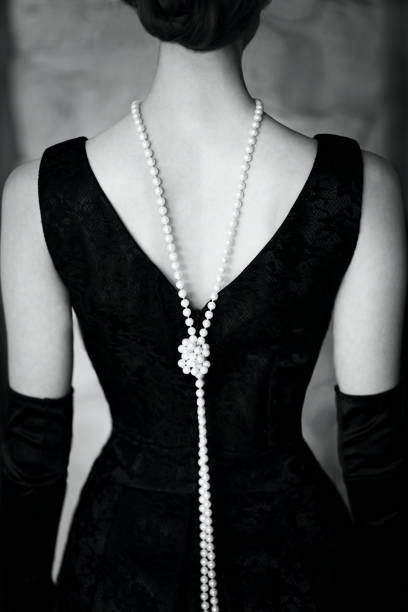 Female figure in a beautiful dress and beads monochrome Beautiful female figure from the back in a black dress and pearls in the style of 20-30 years of the XX century. Black and white photo bead photos stock pictures, royalty-free photos & images