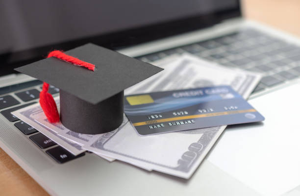 istock Credit card, Academic hat model and Notebook on wooden desk. Online payment by using laptop 1284965554