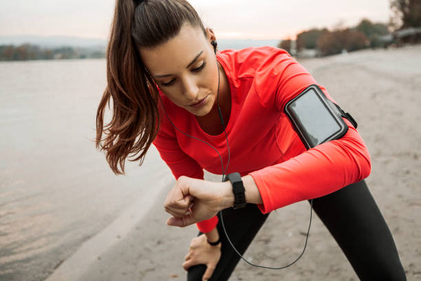 istock Young woman runner in sportswear uses a smart tracker on the beach 1284965762