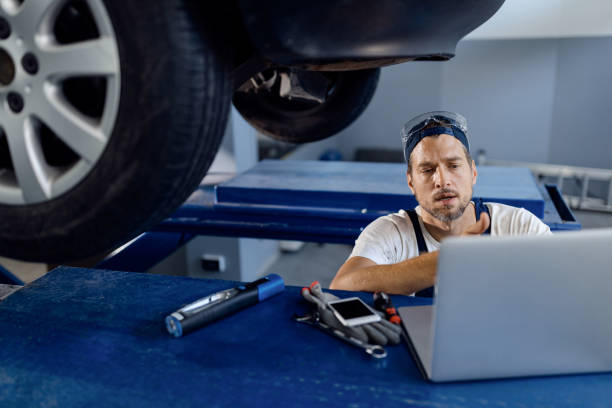 istock Car mechanic using laptop while working at auto repair shop. 1284969551