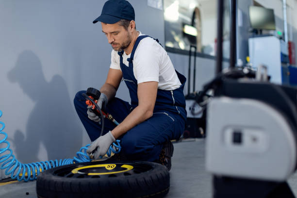 istock Auto mechanic checking pressure in car tire in a workshop. 1284969877