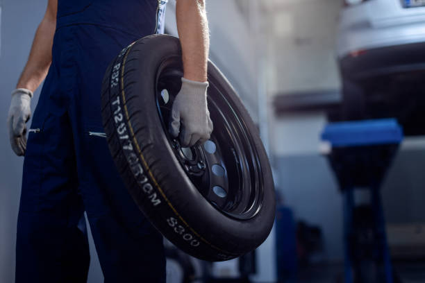 istock Unrecognizable auto mechanic holding car tire in a workshop. 1284969883