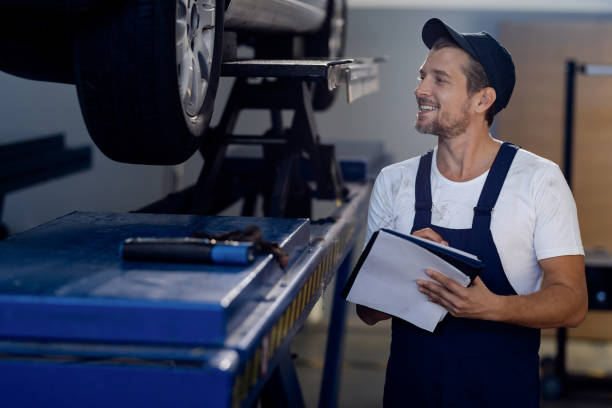istock Happy mechanic taking notes while examining car in auto repair shop. 1284969900