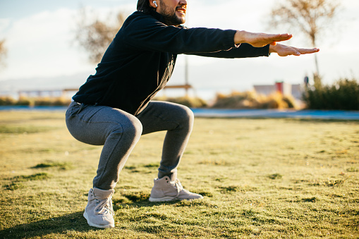 Athletic man on the grass and stretching his leg after sports training.