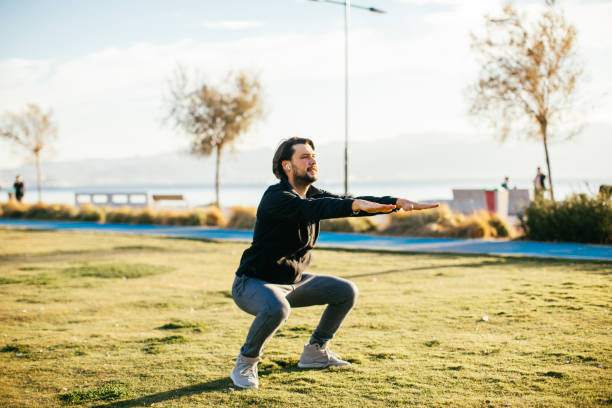 istock Young caucasian man performing squats before jogging on footpath in park. 1284970583
