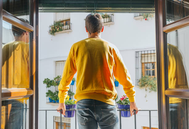 istock Boy standing on a balcony facing the street in a yellow sweatshirt 1284970598