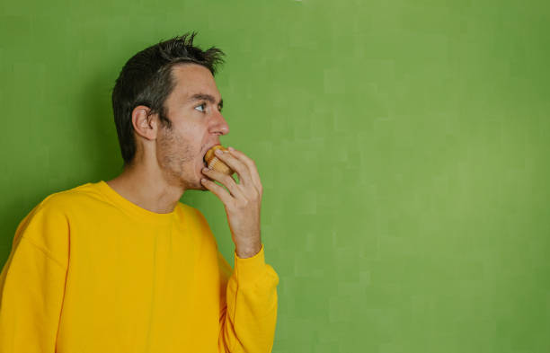 istock Young boy with yellow sweatshirt biting a cupcake he holds in his hand 1284970628