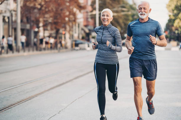 senior man och senior kvinna jogging sida vid sida på gatan - aktiva pensionärer bildbanksfoton och bilder