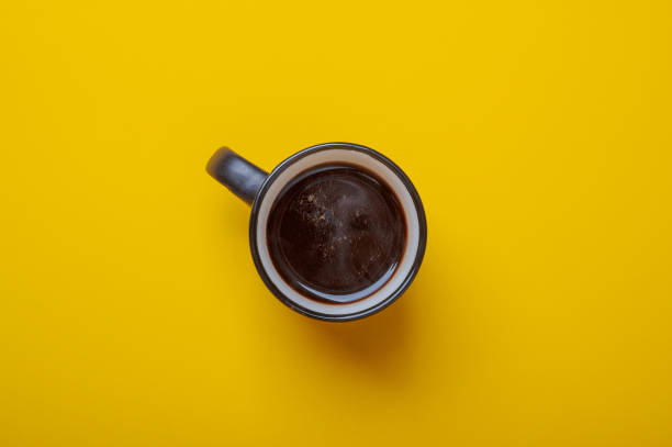 istock black cup with coffee on yellow background top view 1284971879