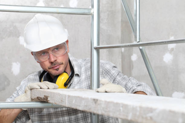 man work, professional construction worker  with scaffolding, safety hard hat, hearing protection headphones, gloves and protective glasses. on interior building site background