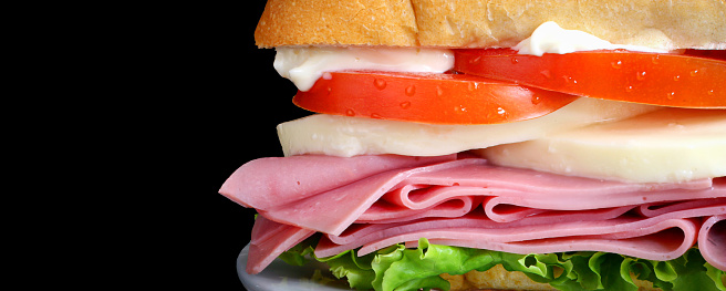 Portion of a delicious sandwich, made with sourdough bread, mayonnaise, tomatoes, fresh white cheese, ham and lettuce.
