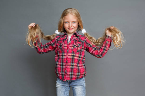istock Little girl with ponytails standing isolated on grey looking camera playful 1284980247