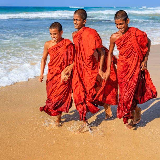 Three Sri Lankan young buddhist monks walking on the beach near Galle, Sri Lanka