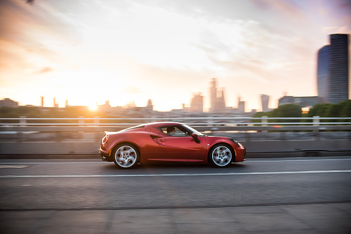 London, United Kingdom June 20, 2020: Alfa Romeo 4C driving in motion on Waterloo Bridge at sunrise.