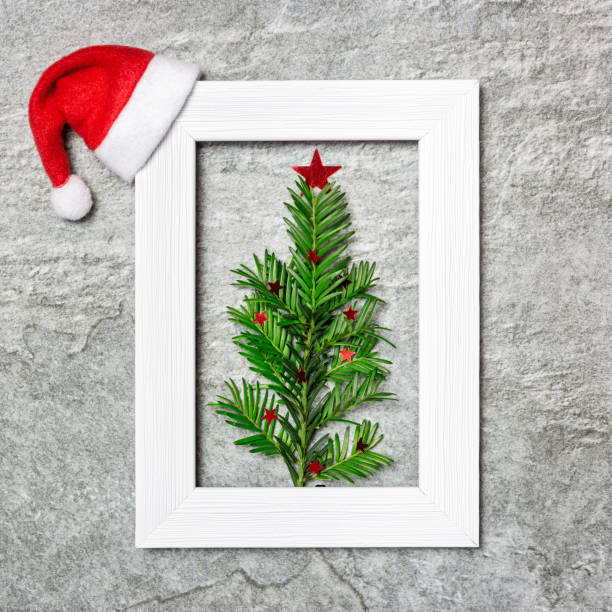 Christmas composition on gray stone table Minimalist Christmas tree made of evergreen plant in white photo frame. Creative flat lay composition. Winter holidays concept. Diy Mobile Frame with Christmas Tree stock pictures, royalty-free photos & images