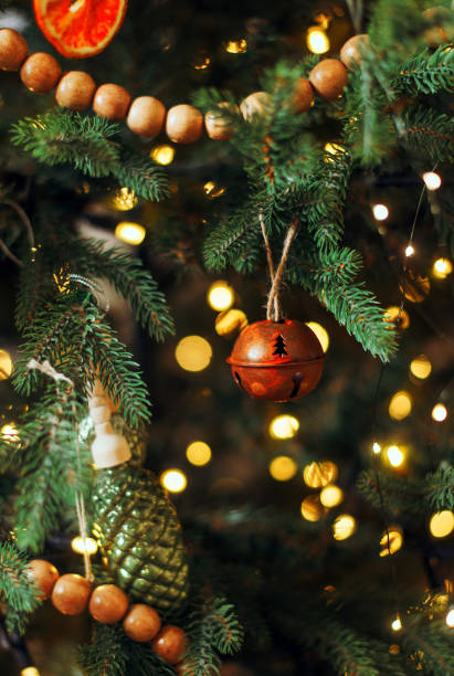 istock A single red Christmas bell hangs on a green christmas tree with warm lights. The ball has stars cut out of the metal. 1284984483