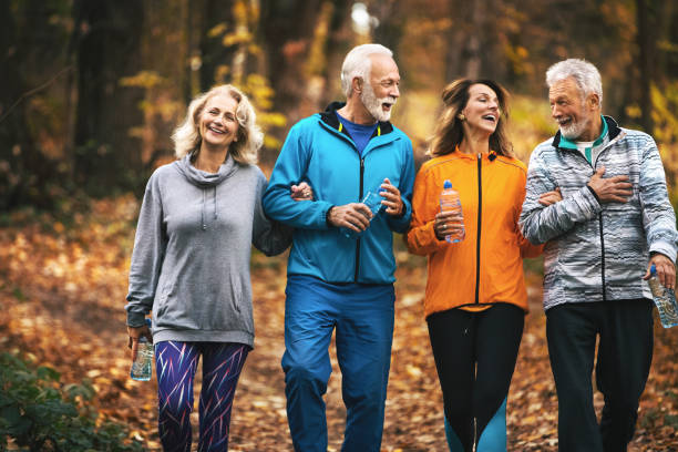 group of mature folks walking a road in a forest. - walking exercising relaxation exercise group of people imagens e fotografias de stock