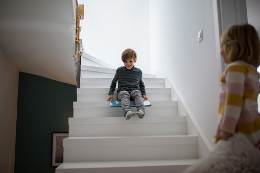It's so fun fun at home, boy sliding down stairs at home