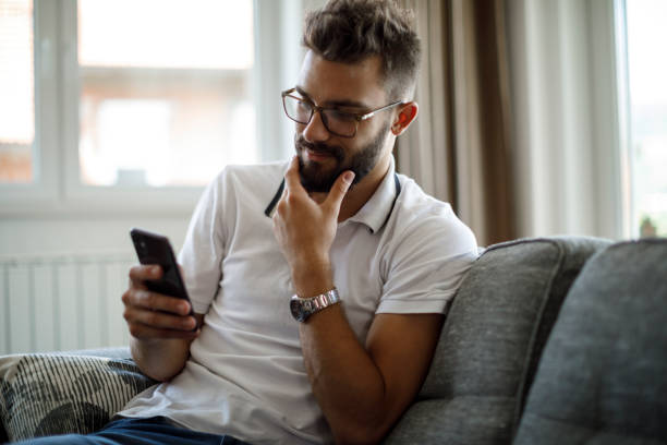 istock Smiling young man using mobile phone at home 1284991980
