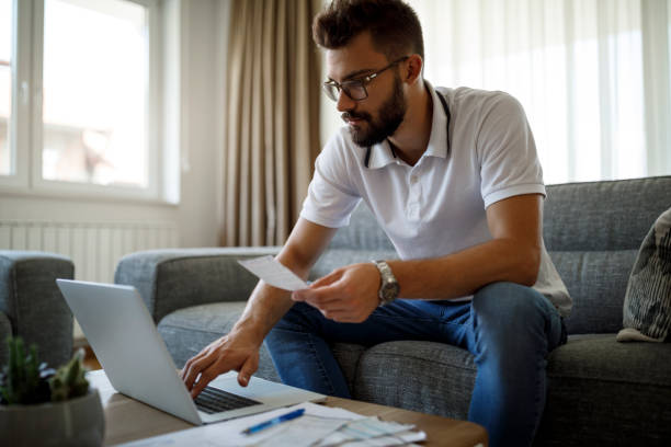 istock Young man paying bills on his laptop at home 1284992047