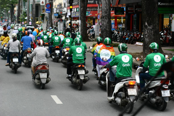 Taxi grabbike drivers in traffic Vietnam 30 october 2020 group of Taxi grabbike grab drivers in traffic with rainbow flag - Vietnam - 30 october 2020 vietnamese man taxi motorbike driver stock pictures, royalty-free photos & images