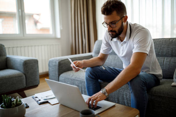 istock Young man paying bills on his laptop at home 1284992209