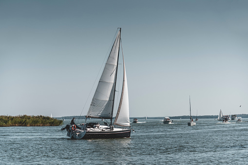 The yacht passes through the crowded Przeczka strait, which connects Mikołajskie Lake with the Śniardwy Lake in the Masurian Lake District.