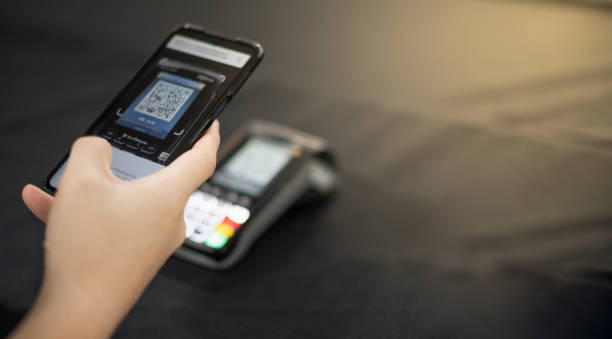 Female hand scanning the QR code with mobile phone for pay at the shop in the concept contactless payment. stock photo
