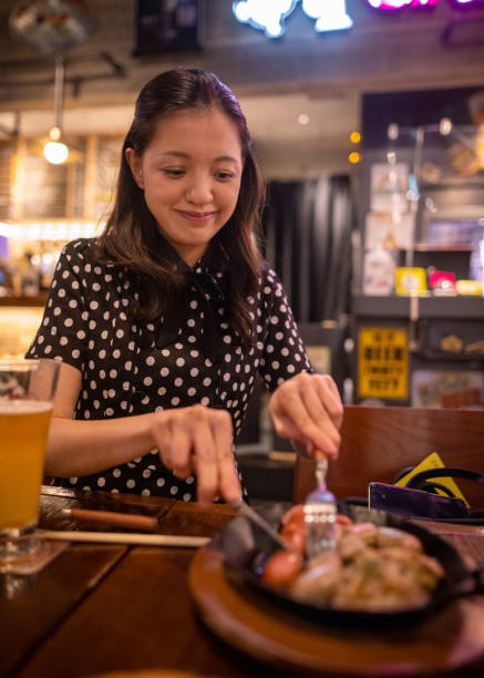 istock Young woman cutting sausage in restaurant for dinner 1284998320