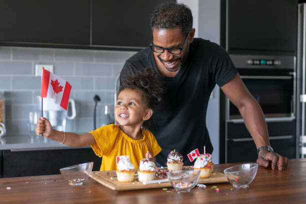 padre e hija decoran cupcakes mientras celebran el día de canadá en casa - house home interior flag usa fotografías e imágenes de stock