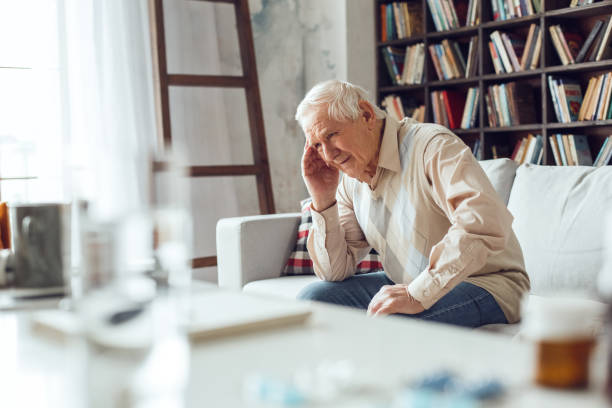 istock Senior man alone sitting at library table close-up having migraine upset 1284999020