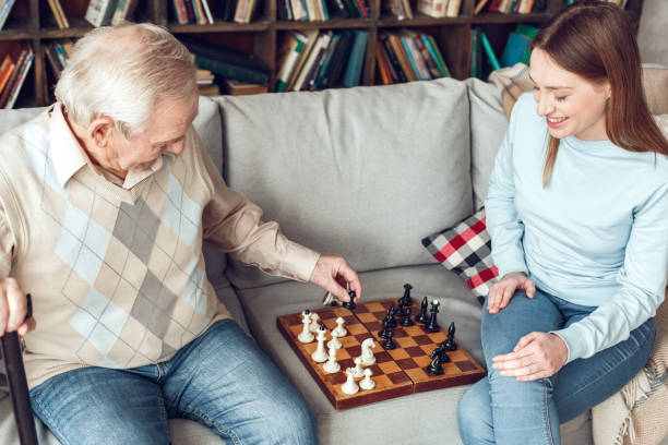 istock Father and daughter at home library sitting moving pieces on chess board playing cheerful 1284999033
