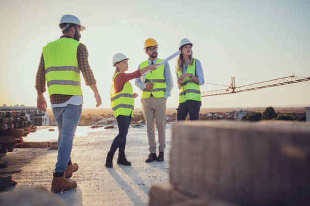 From an idea to a completed project Comparing with the blueprints, a team of experts is evaluating the realization on the construction site. For their own safety, all members have yellow vests and hard hats. civil engineer stock pictures, royalty-free photos & images