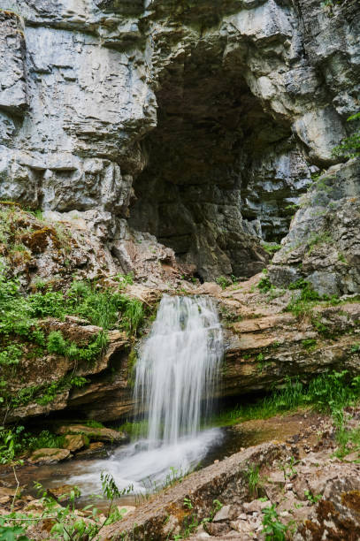 istock view of a small mountain river waterfall among large cobblestones from a cliff. 1284999507