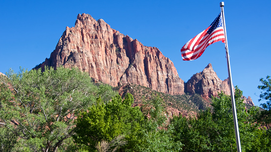The US flag against the red sandstone cliffs of Zion Canyon in Zion National Park, Utah.