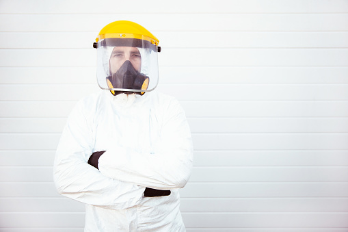 Man in protective suit holds a disinfection canister. epidemiologist in protective suit. Protective PPE suit wearing face mask and eyes protection