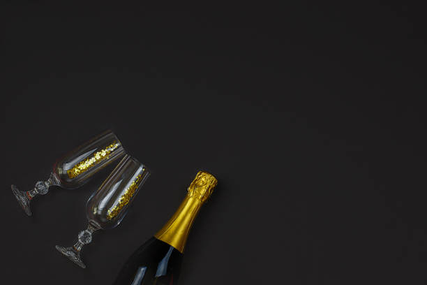 istock Two champagne glasses with confetti on black background. 1285013282