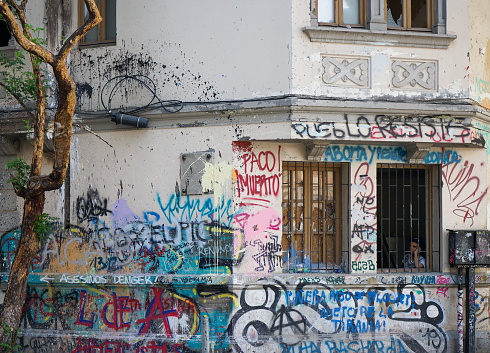 One male, male artist painting a graffiti on the wall on building top.