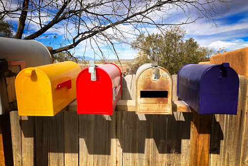 A silver metal mailbox with a large dent and a red flag.