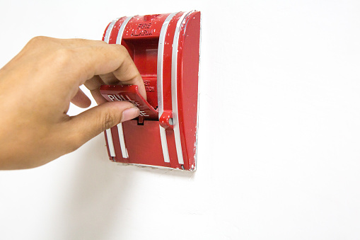 A woman's finger turning on the fire alarm and copy space