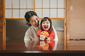 丸い餅にマンダリンオレンジを置くアジアの母と娘