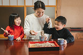 日本の部屋で和食そばと戸子を食べる日本人の母子