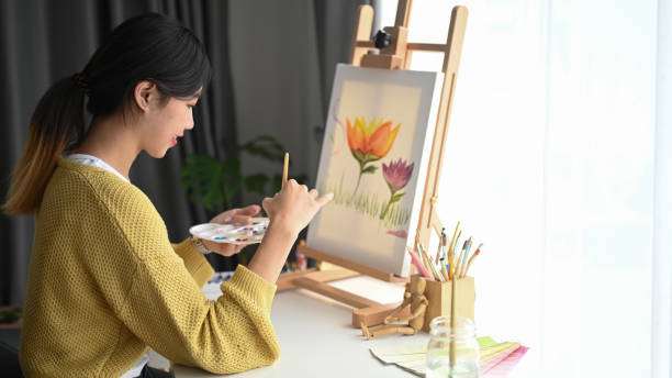 istock A pretty talented female painter with a palette in hands painting on canvas in studio. 1285020678