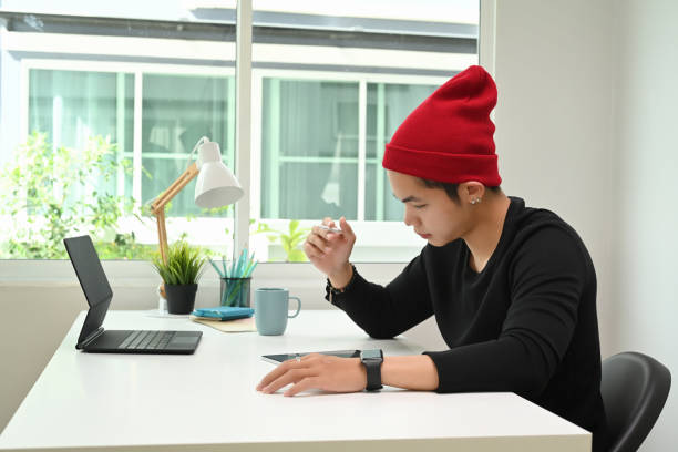 istock A man graphic designer in red wool hat is working on graphic tablet at desk in the office. 1285020716